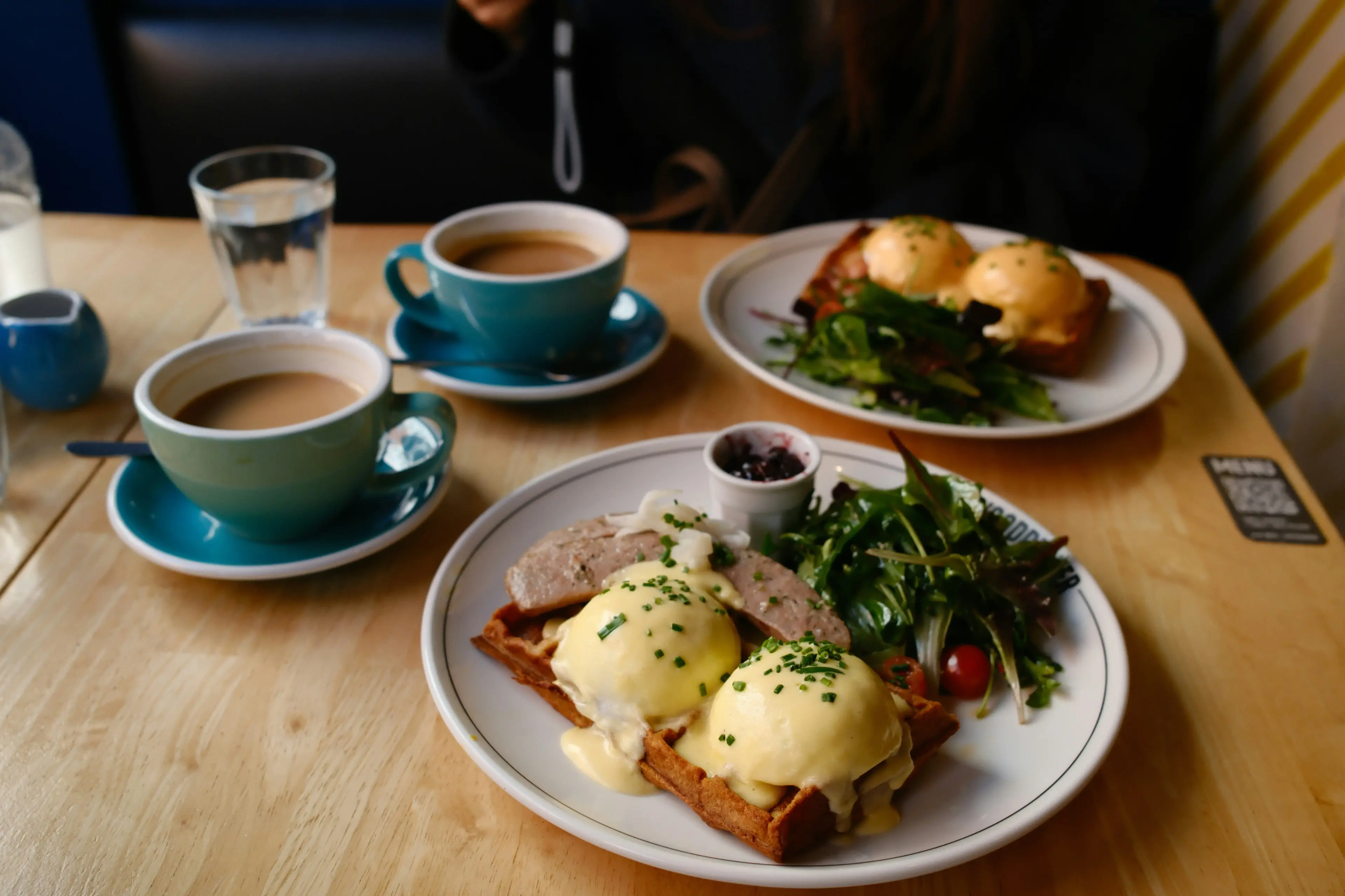 Eggs benedict with coffee at a brunch table