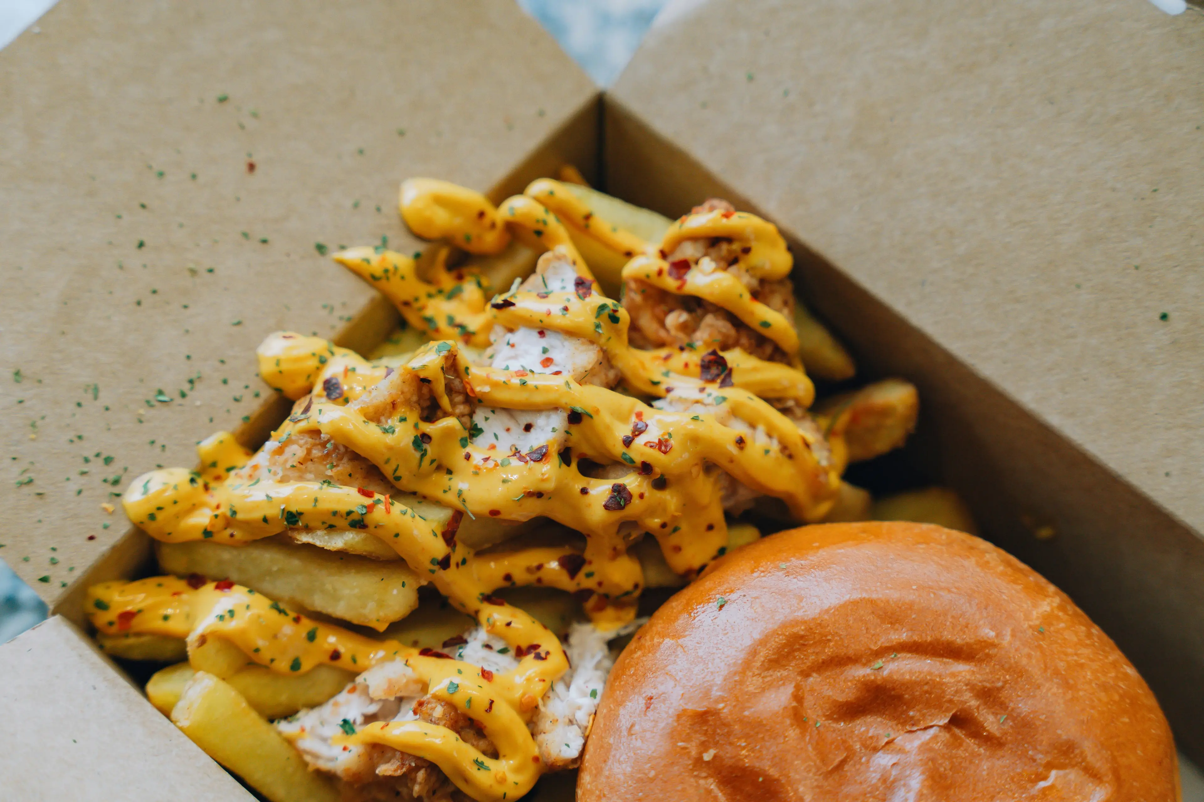 Loaded fries and burger in a takeout box