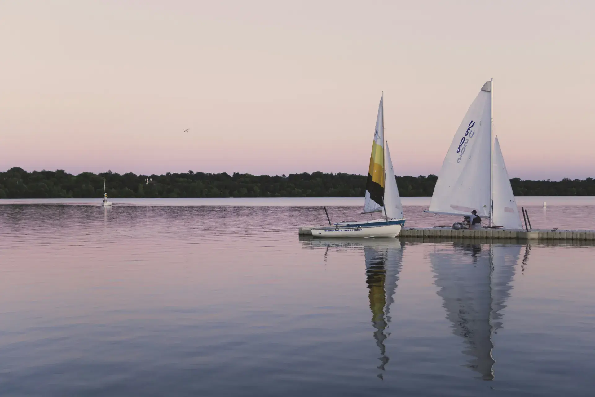 Sailboats on a Minneapolis lake at pink dusk, capturing Fulton's lakeside lifestyle