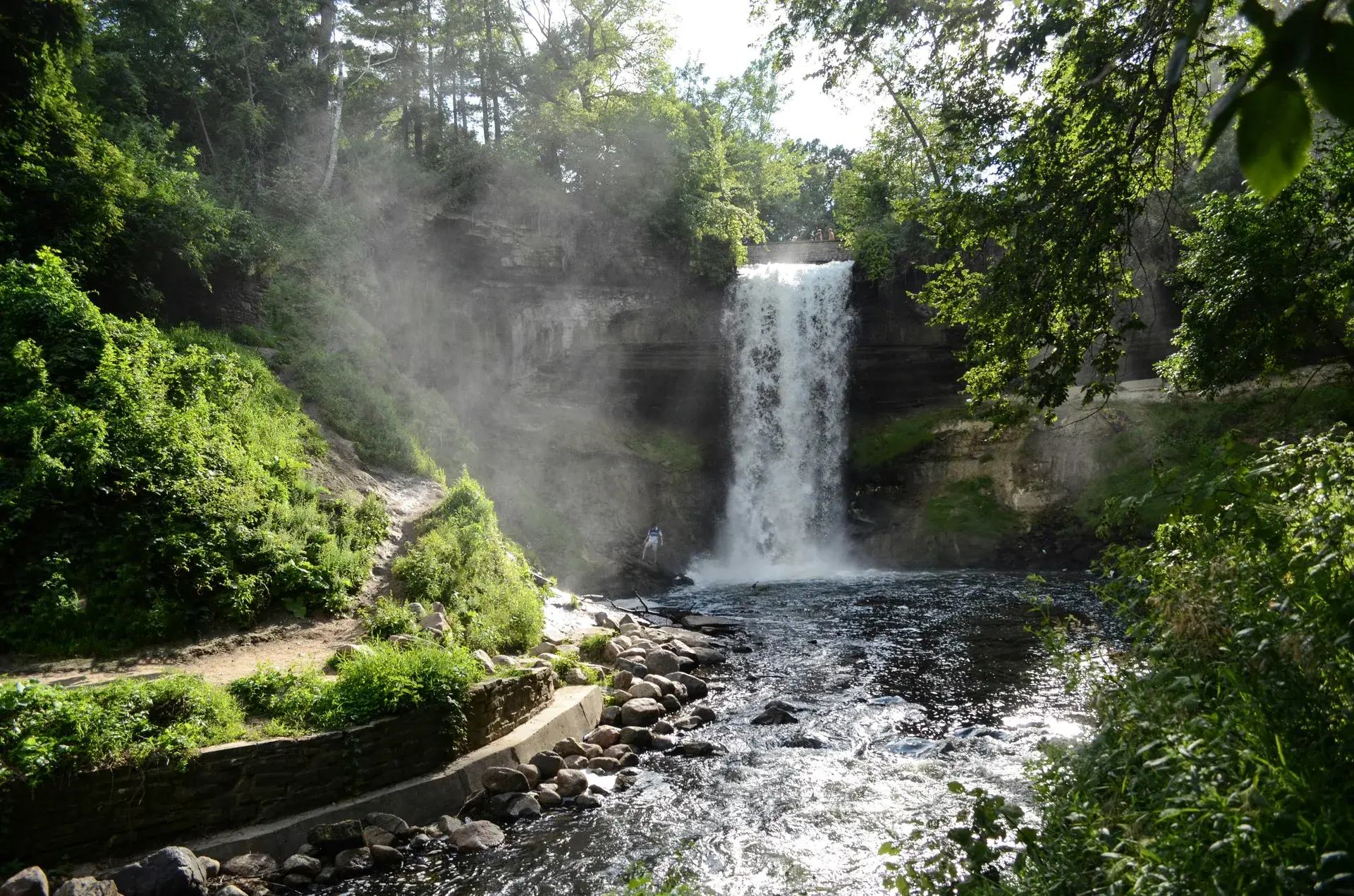 Minnehaha Falls surrounded by lush summer greenery in the Longfellow neighborhood